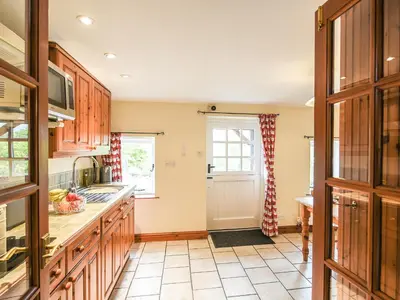a kitchen with wooden cabinets and a window at The Old Coach House -Uk41272 in Great Hanwood