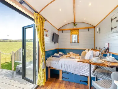 a bedroom in a caravan with a bed and a table at Tulip - Uk42363 in Saint Harmon
