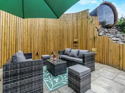 a patio with two couches and an umbrella at The Lodge Spa - Uk47837 in Church Pulverbatch
