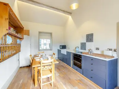 a kitchen with blue cabinets and a table with chairs at Apartment At Llanerchydol Hall in Welshpool