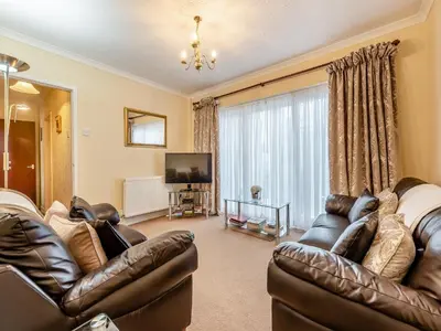 a living room with two leather couches and a television at Snowdrop in Llanerch-Aeron