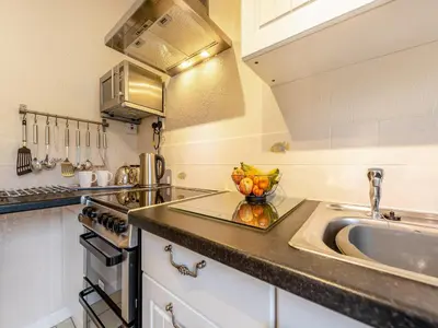 a kitchen with a sink and a bowl of fruit on the counter at Snowdrop in Llanerch-Aeron