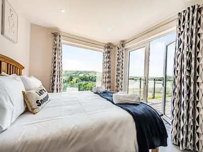 a bedroom with a large bed and a large window at Llwynblyfyn in Llansawel