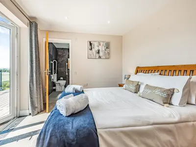 a bedroom with a large bed and a balcony at Llwynblyfyn in Llansawel