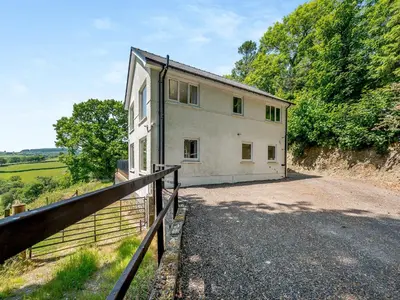 a house on the side of a hill with a fence at Llwynblyfyn in Llansawel