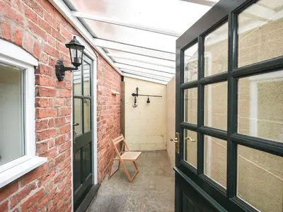 a brick hallway with a door and a chair at The Corn House - Cottage in Great Hanwood