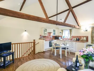 a living room with a kitchen and a table at The Corn House - Cottage in Great Hanwood