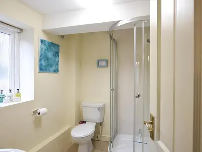 a bathroom with a toilet and a glass shower at The Corn House - Cottage in Great Hanwood