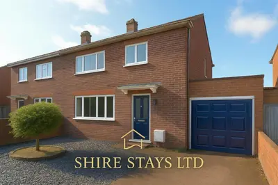 a brick house with a blue garage door at MODERN 3 BEDROOM PROPERTY WITH FREE DRIVEWAY PARKING by SHIRE STAYS in Shrewsbury