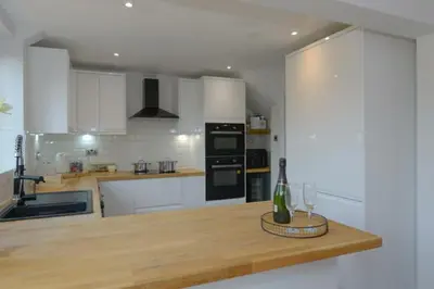 a kitchen with white cabinets and a counter with wine glasses at MODERN 3 BEDROOM PROPERTY WITH FREE DRIVEWAY PARKING by SHIRE STAYS in Shrewsbury
