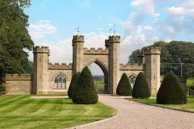 an entrance to a castle with trees in the grass at Bryngwilla Gate Lodge in Oswestry