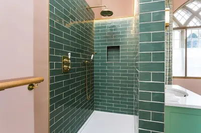 a bathroom with a shower with green subway tiles at Bryngwilla Gate Lodge in Oswestry