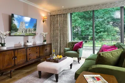a living room with green furniture and a large window at Bryngwilla Gate Lodge in Oswestry