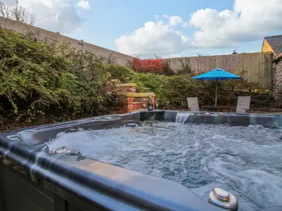 a hot tub in a yard with an umbrella at The Cart House in Shrewsbury