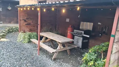 a picnic table and a grill with a picnic table and a bench at Bunkhouse Accommodation in the Heart of Snowdonia in Dolgellau