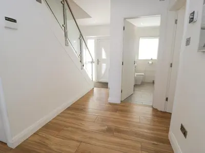 a hallway with white walls and wood flooring at The Gables in Tywyn