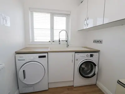 a kitchen with a washing machine and a sink at The Gables in Tywyn