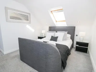 a bedroom with a large bed with white sheets at The Gables in Tywyn
