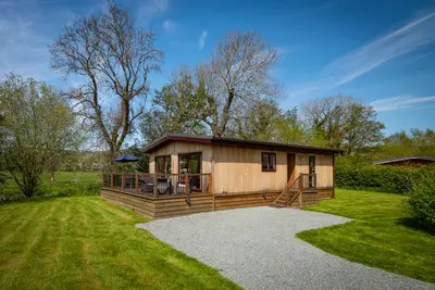 a small wooden cabin in a field of grass at Ash Lodge in Craven Arms