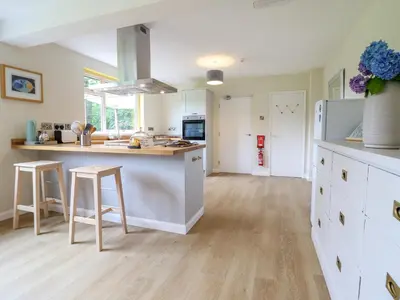 a kitchen with white cabinets and a counter with stools at The Wardens House in Newtown