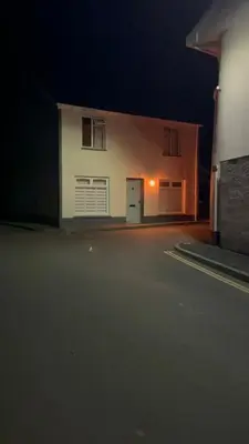 a white building with a garage at night at 3 bedroom cottage Brecon sleeps 4 in Brecon