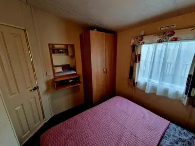 a small bedroom with a pink bed and a window at Gorgeous Sea Viev 3 Bedroom Delta Bromley Deluxe in Aberystwyth