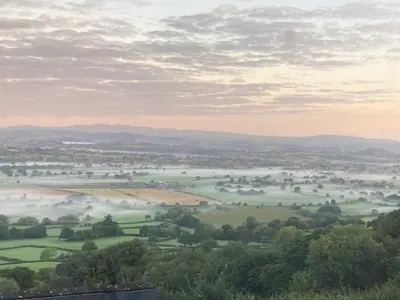 a view of a field with fog in the distance at Trinity Cottage in Welshpool