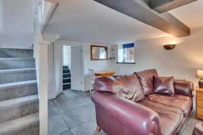 a living room with a leather couch and stairs at Trinity Cottage in Welshpool