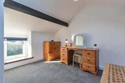 a bedroom with a wooden dresser and a mirror at Trinity Cottage in Welshpool