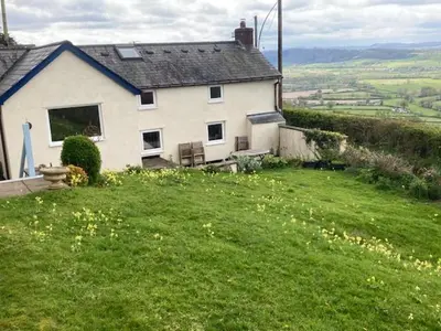 a house sitting on top of a green field at Trinity Cottage in Welshpool