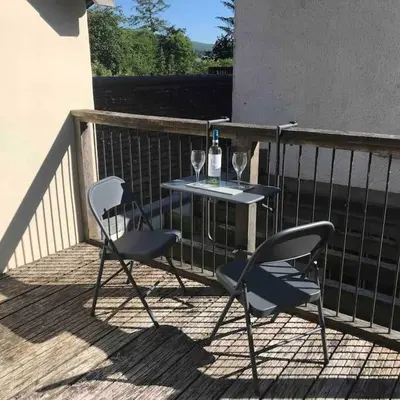 two chairs and a table with wine glasses on a balcony at Craig Fach Coach House in Builth Wells