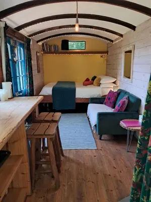 a room with two beds and a couch and a table at Hilltop Train Carriage with a View in Machynlleth