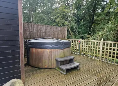 a wooden deck with a hot tub and a stool at Glan yr Afon Un - Relax Recuperate Enjoy in Welshpool