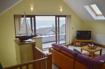a living room with a couch and a large window at Ruby's Watch in Barmouth