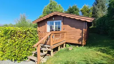 a wooden cabin with a porch and a deck at Cosy log cabin in Snowdonia 167 in Trawsfynydd