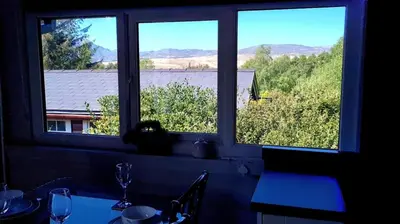 two windows in a room with a table with a view at Cosy log cabin in Snowdonia 167 in Trawsfynydd