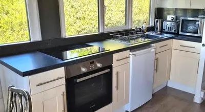 a kitchen with white cabinets and black counter tops at Cosy log cabin in Snowdonia 167 in Trawsfynydd
