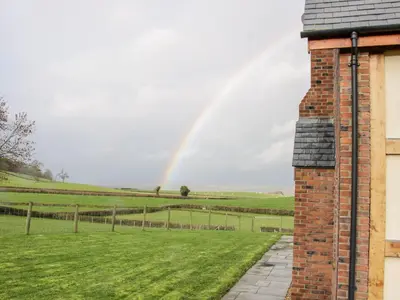 a rainbow in the sky over a field with a house at White House in Montgomery