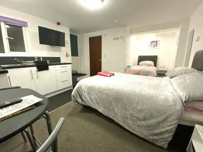 a room with two beds and a table and a kitchen at Cosy Studio - Town centre flat with free nearby parking in Shrewsbury