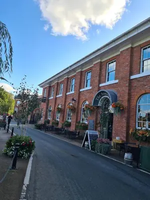 a red brick building with benches and flowers on a street at Cosy Studio - Town centre flat with free nearby parking in Shrewsbury