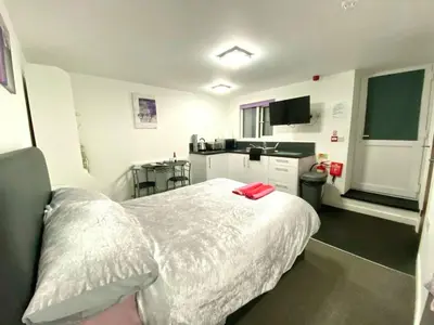 a bedroom with a white bed and a kitchen at Cosy Studio - Town centre flat with free nearby parking in Shrewsbury