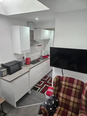 a kitchen with white cabinets and a chair in a room at Cosy Corner - Town centre flat with free nearby parking in Shrewsbury