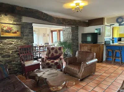 a living room with leather furniture and a stone wall at Happy Horse Cottages in Sennybridge