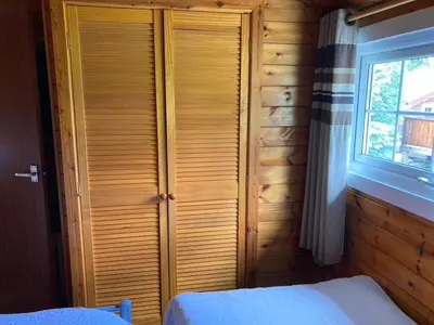 a bedroom with a wooden closet with a bed and a window at Cosy log cabin in Snowdonia 357 in Trawsfynydd