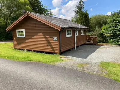 a large log cabin with a driveway at Cosy log cabin in Snowdonia 357 in Trawsfynydd