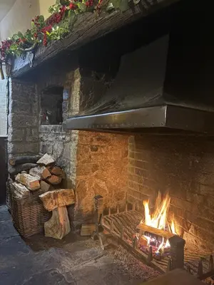 a large brick fireplace with fire in it at The Harp Inn in Old Radnor