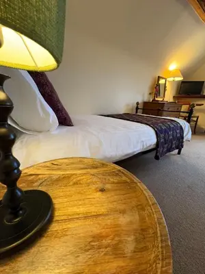 a bedroom with a bed and a table with a lamp at The Harp Inn in Old Radnor