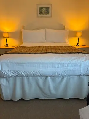 a bedroom with a large bed with two lamps at The Harp Inn in Old Radnor