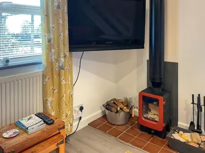 a living room with a wood stove and a television at The Hideaway in Tregaron