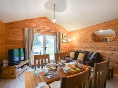 a dining room with a table and a couch at Llwynog Lodge in Montgomery